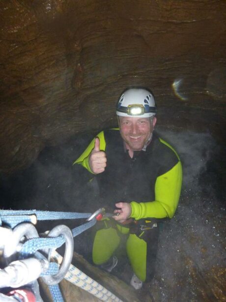 En guide der er på vej dybt ned i en grotte med en gruppe studerende i juni måned